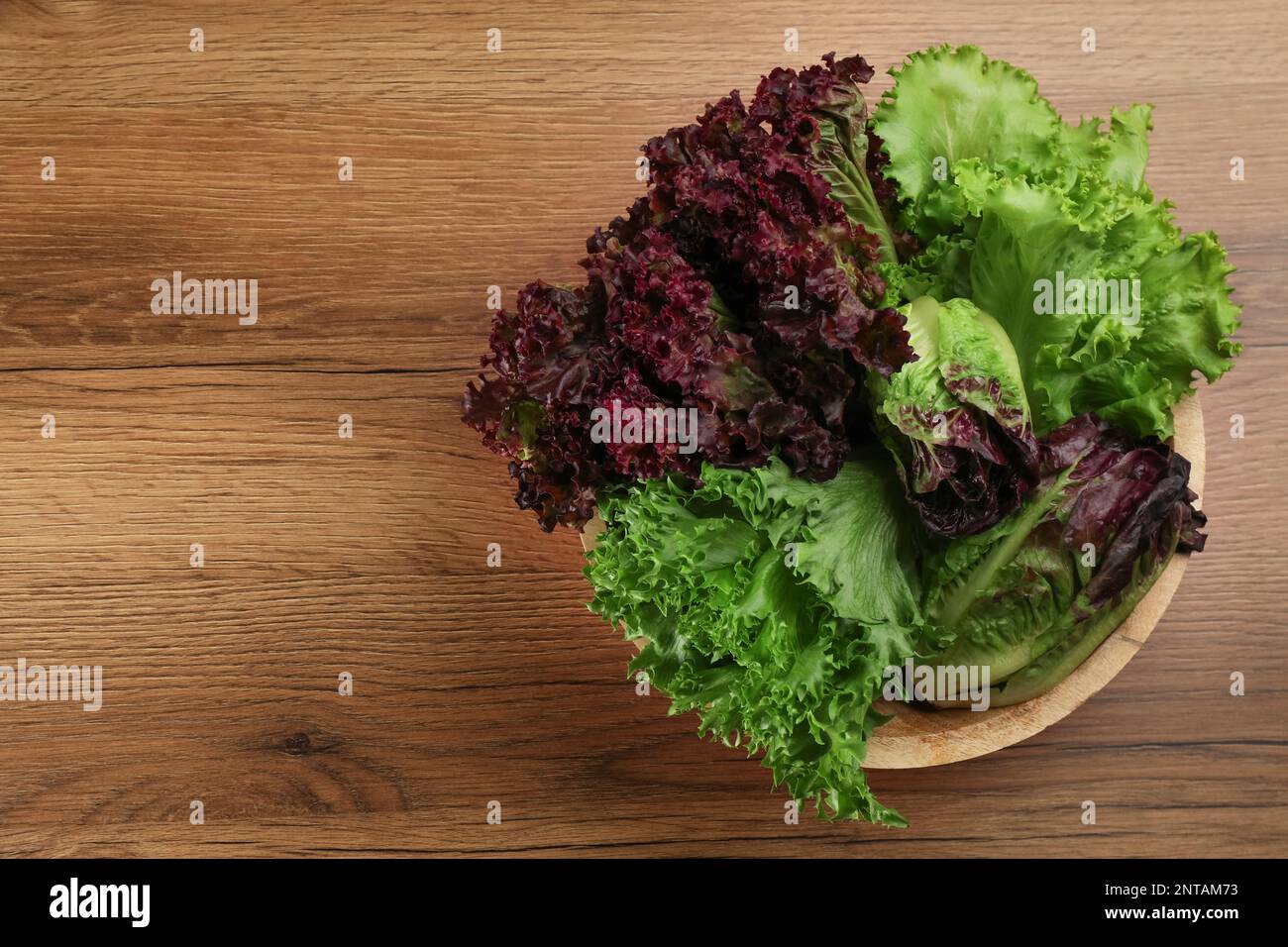 Different sorts of lettuce on wooden table, top view. Space for text ...
