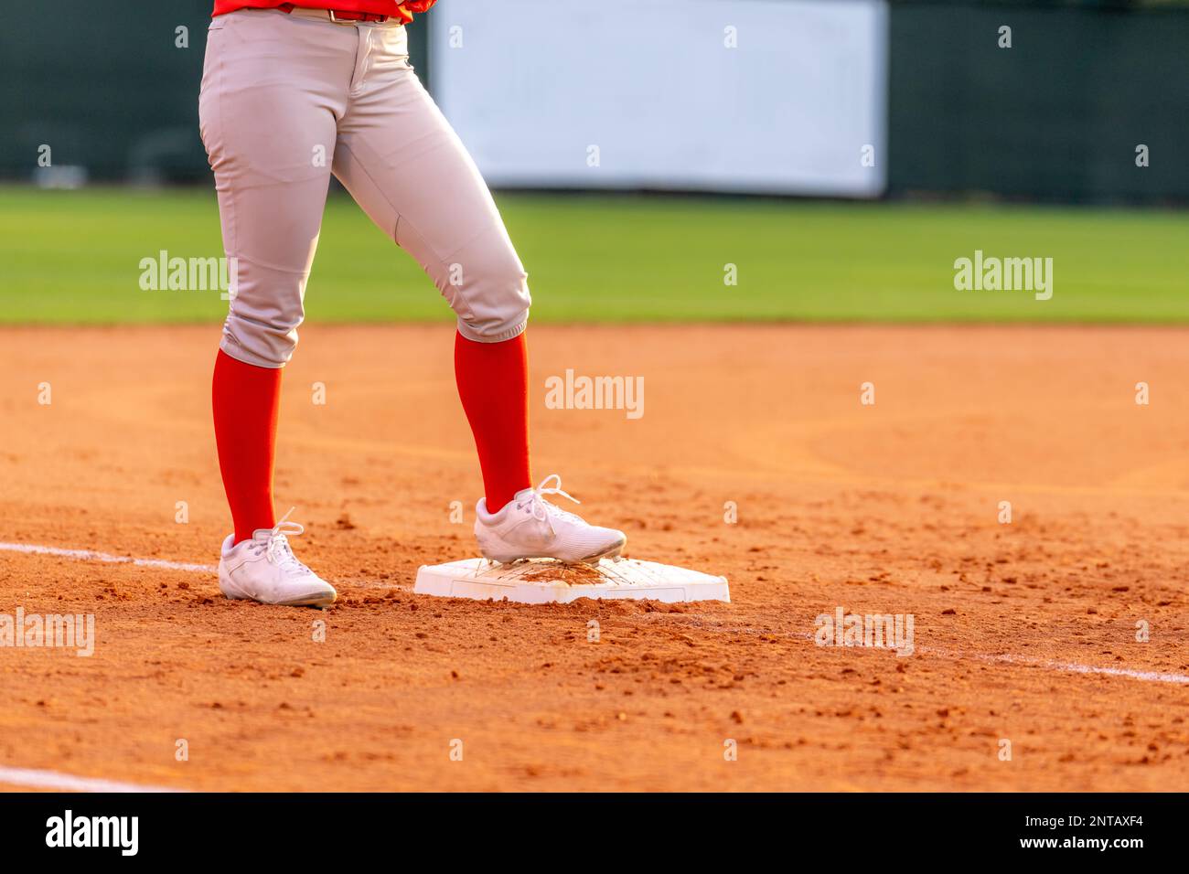 Lower half of a softball player ready to play, waiting on second base