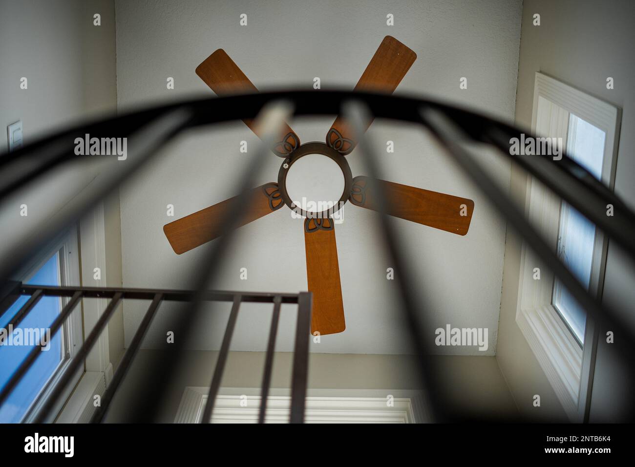 Wooden Stationary Ceiling fan at the top of a spiral staircase Stock Photo