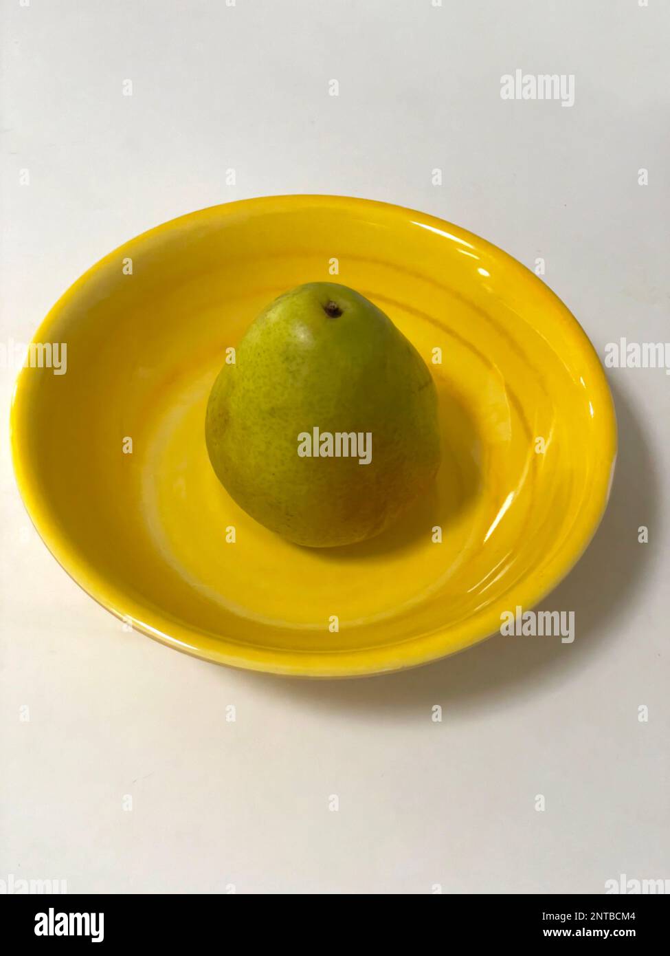 A green pear on a yellow plate. Stock Photo
