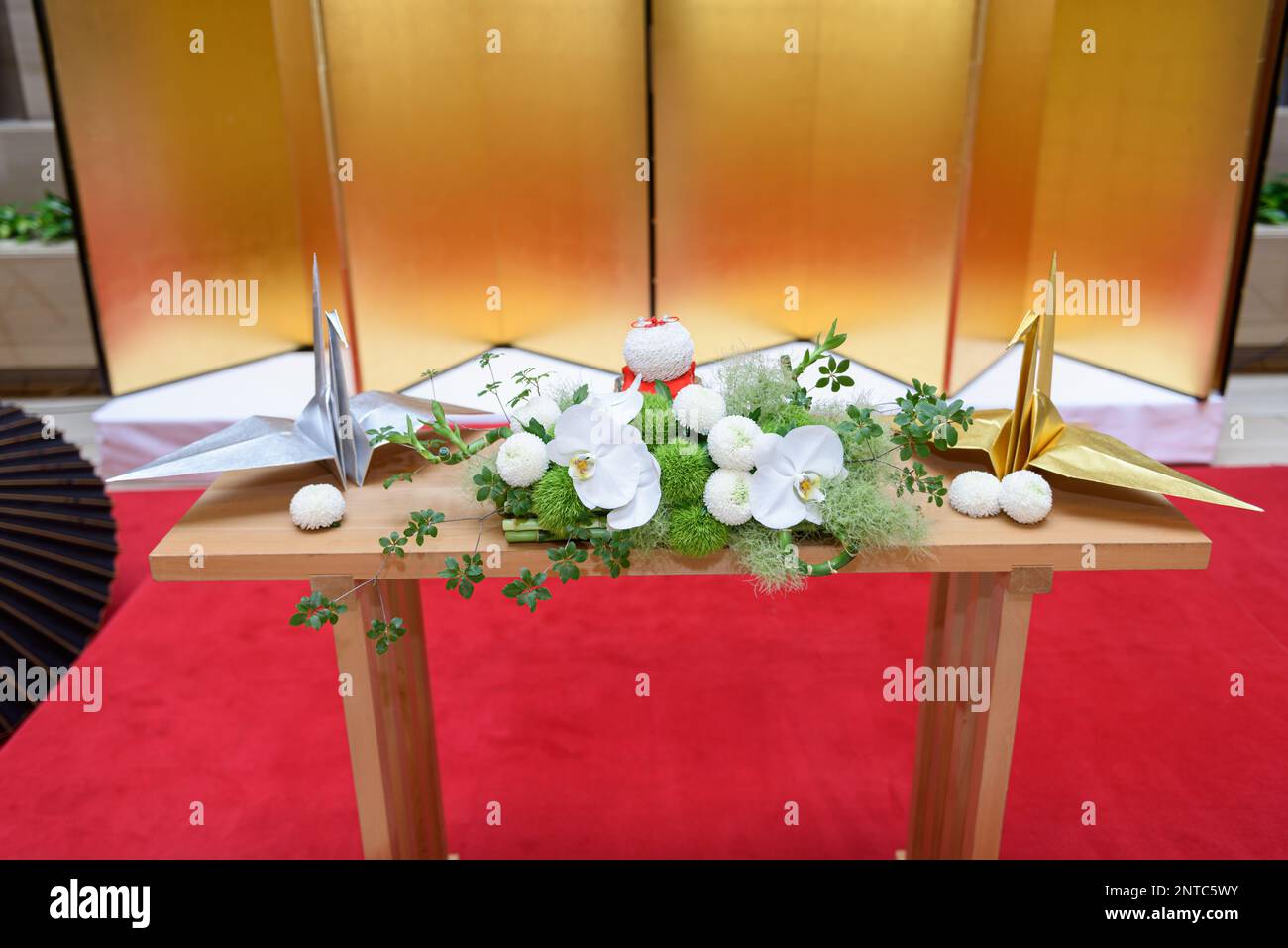 Japanese origami cranes and a white flower arrangement on a table. Japanese wedding decoration. Stock Photo