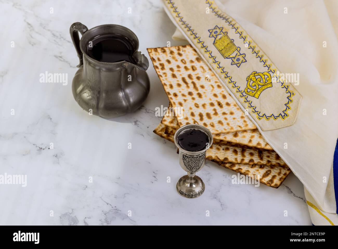 Traditional Passover food consists of unleavened matzah bread and kosher kiddush cup wine during Pesach Stock Photo