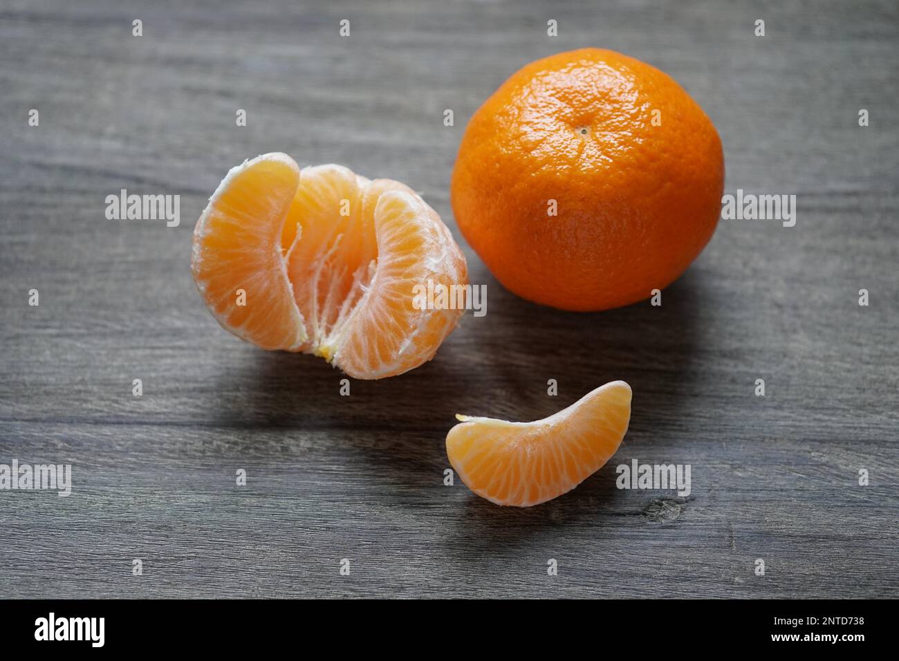 peeled and unpeeled clementines or mandarin oranges on rustic wooden