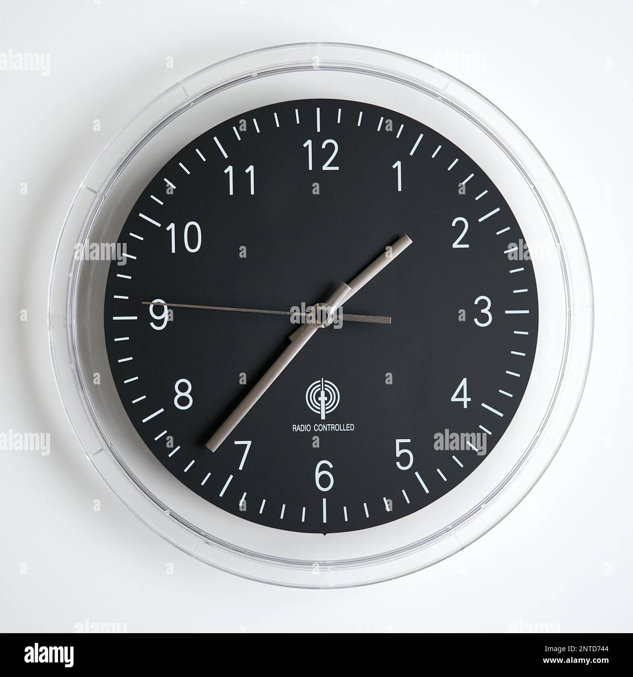 radio controlled wall clock with white numbers on black clock face Stock Photo