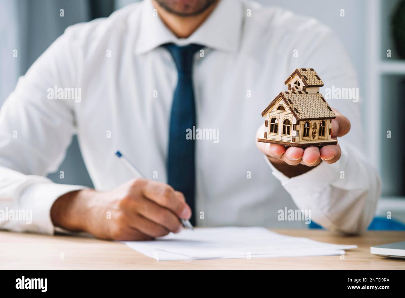 writing real estate agent holding house. High resolution photo Stock