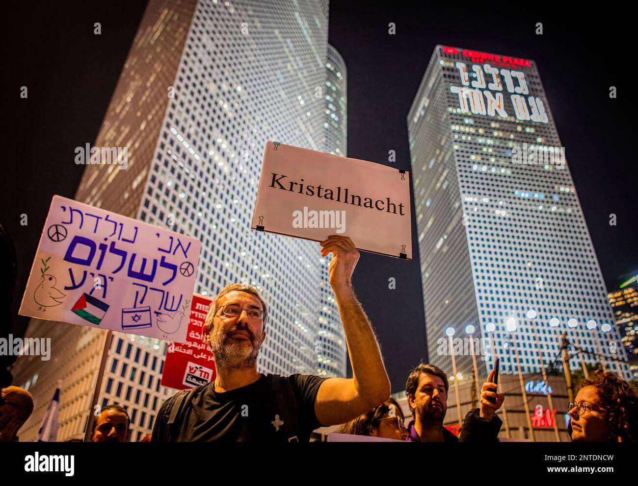 Tel Aviv, Israel. 27th Feb, 2023. Protestor holds a placard that says 'I was born for peace to come, and Night of Broken Glass' during the demonstration. Demonstrators in Tel Aviv protested against the violence committed by settlers in the West Bank town of Huwara the previous evening following a terror attack on Sunday which resulted in the deaths of two Israelis from the Har Bracha settlement. Credit: SOPA Images Limited/Alamy Live News Stock Photo