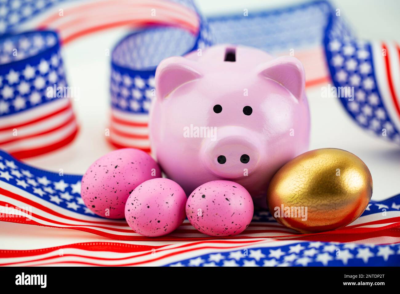 American stars and stripes, red, white, and blue surround feminine  bank accented by gold egg and three, pink eggs support women's success Stock Photo
