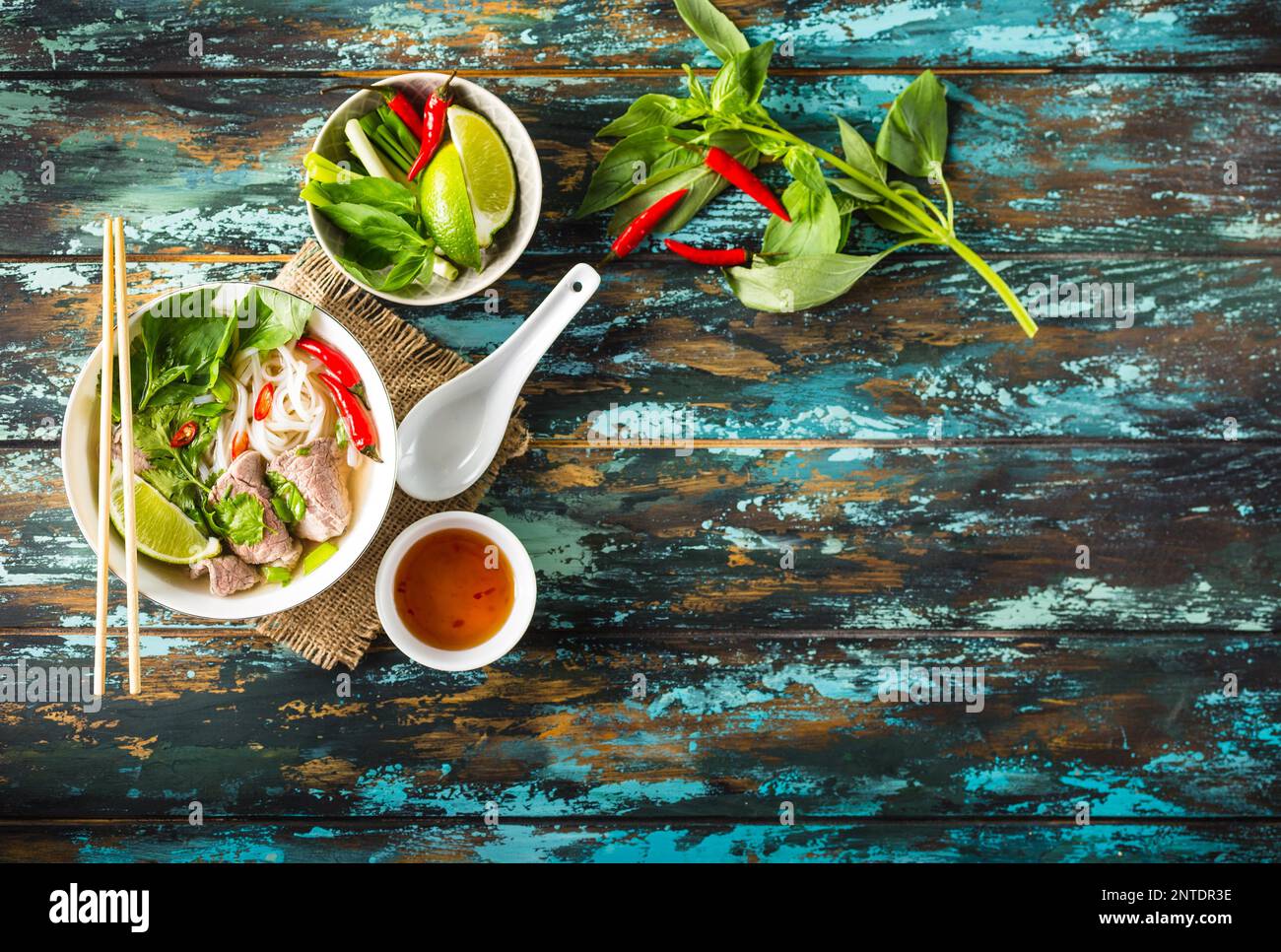 Traditional Vietnamese soup Pho bo with herbs, meat, rice noodles, broth. Pho bo in bowl with chopsticks, spoon. Space for text. Top view. Asian soup Stock Photo