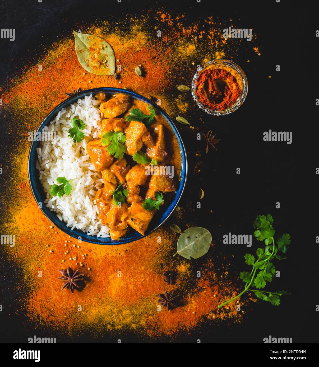 Indian Butter chicken with basmati rice, bowl, spices, black background