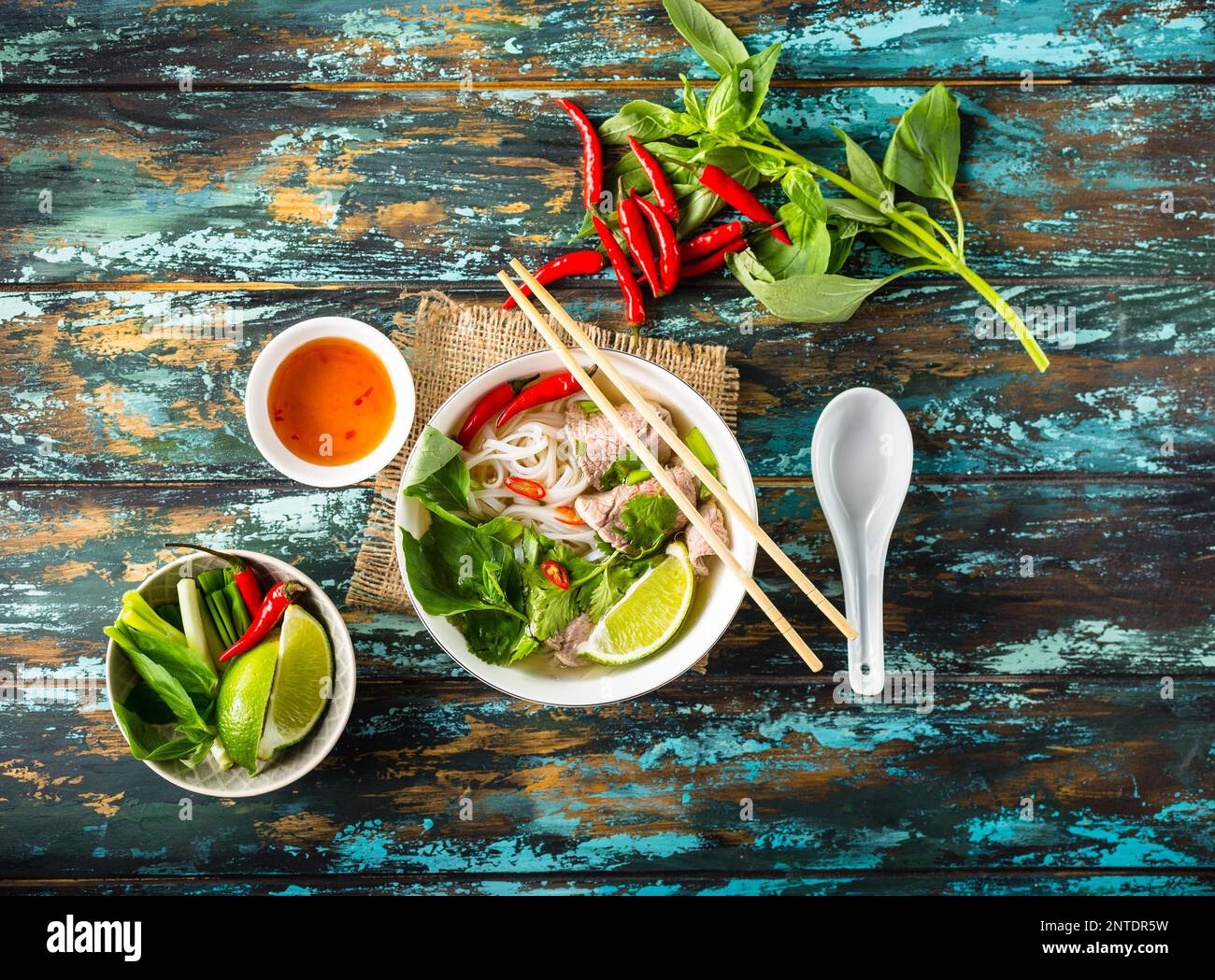 Traditional Vietnamese soup Pho bo with herbs, meat, rice noodles, broth. Pho bo in bowl with chopsticks, spoon. Top view. Asian soup Pho bo, wooden Stock Photo