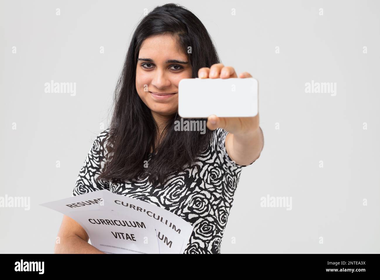 Half length portrait of newly graduated - Half Length Portrait Of Newly Graduated Indian Student Clutching All The Resumes She Has Prepared And Showing Us The Blank Screen Of A Cell Phone Sugg 2NTEA3X 