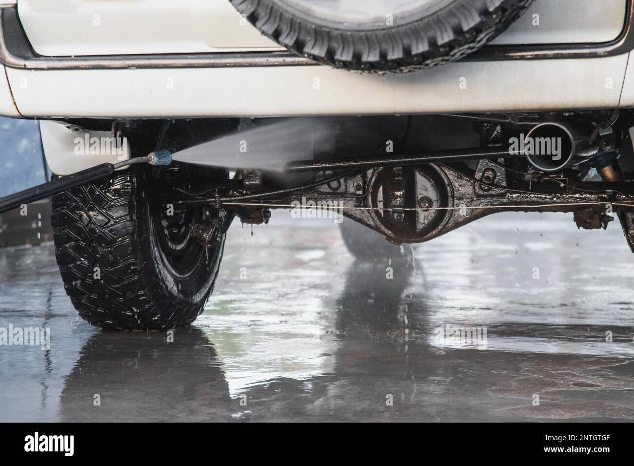 Washing the rear suspension of an SUV with a highpressure water jet at a selfservice car wash
