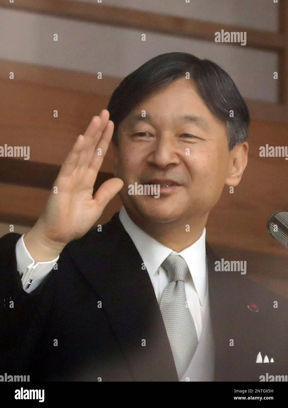 Japan's Emperor Naruhito waves his hand to people on the balcony of the