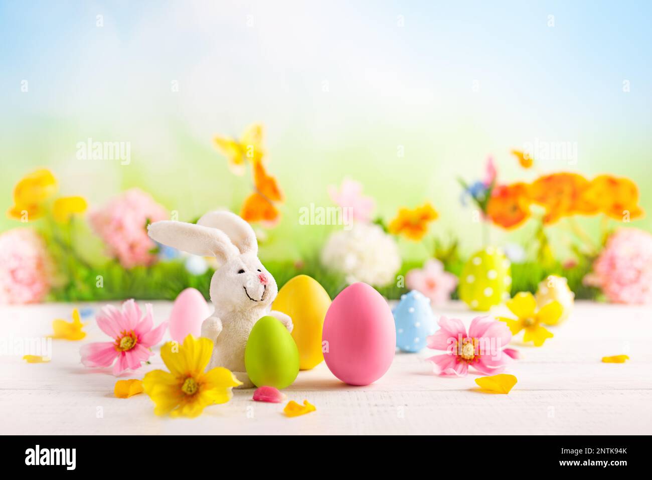 Happy Easter greeting card. Easter eggs, bunny  and spring flowers on table for decoration home for Easter. Stock Photo