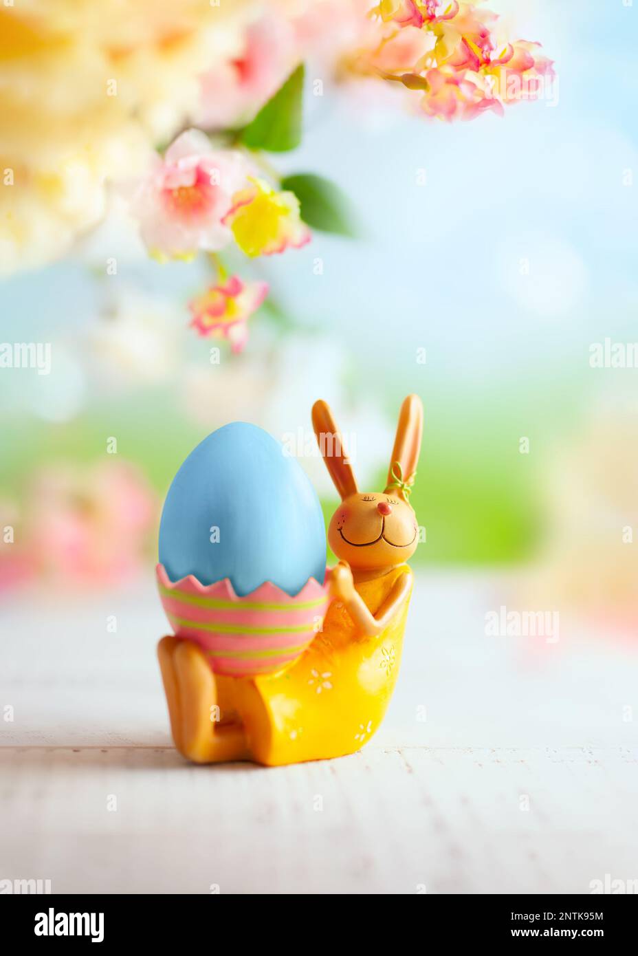 Easter decoration with bunny, Easter eggs and beautiful spring flowers on a blurred light background. Easter concept with copy space. Stock Photo