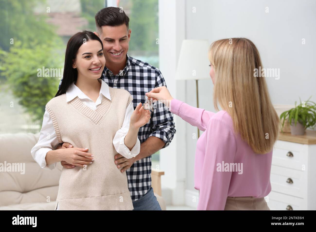Real estate agent giving house key to couple at home Stock Photo - Alamy