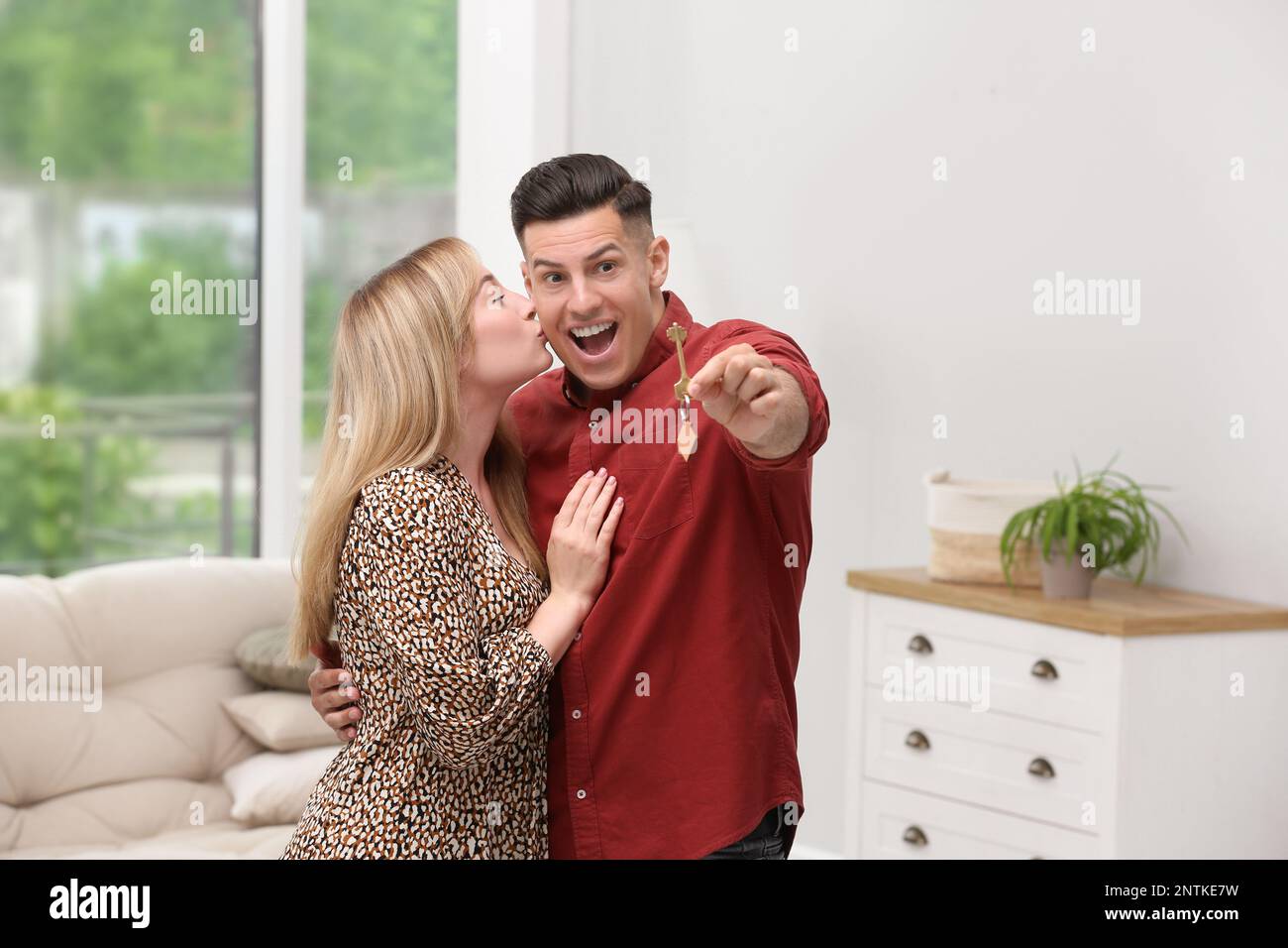 Happy couple with key from their new house indoors Stock Photo - Alamy