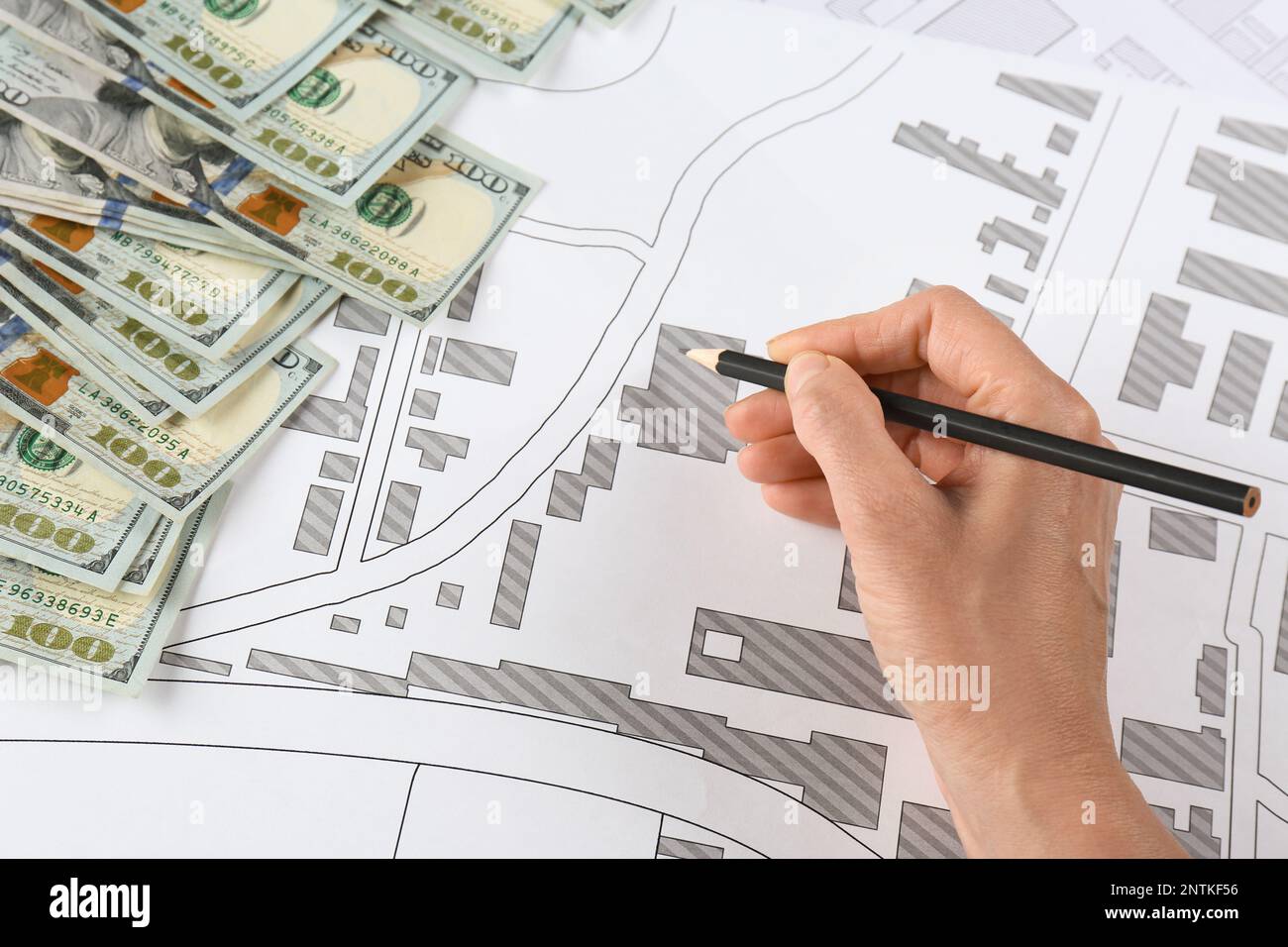 Cartographer with money drawing cadastral map, closeup Stock Photo