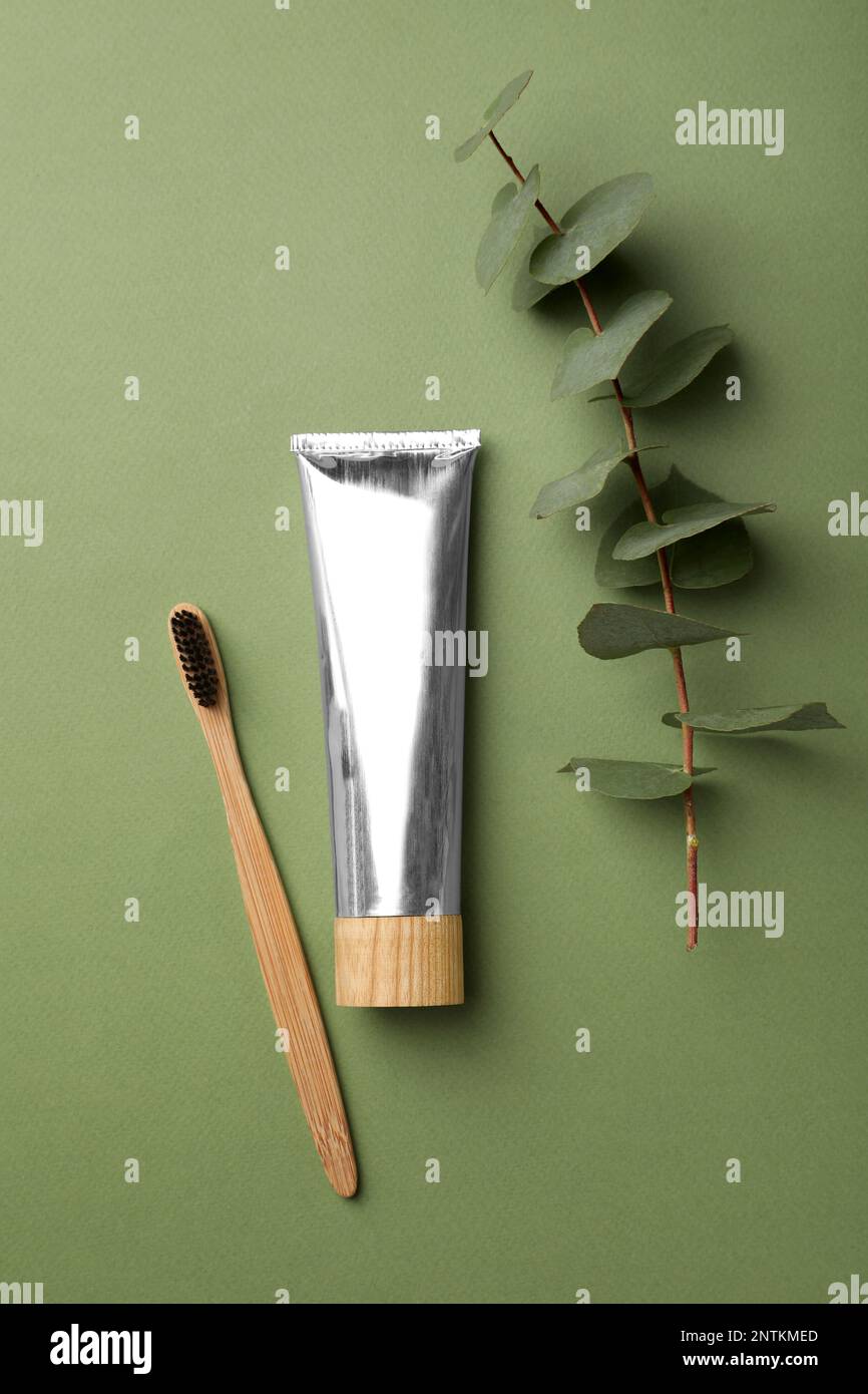 Bamboo toothbrush and tube of paste on green background, flat lay ...