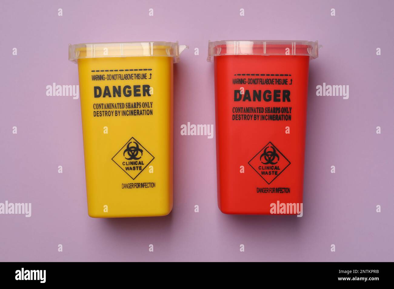 Sharps containers for used syringe on violet background, flat lay Stock