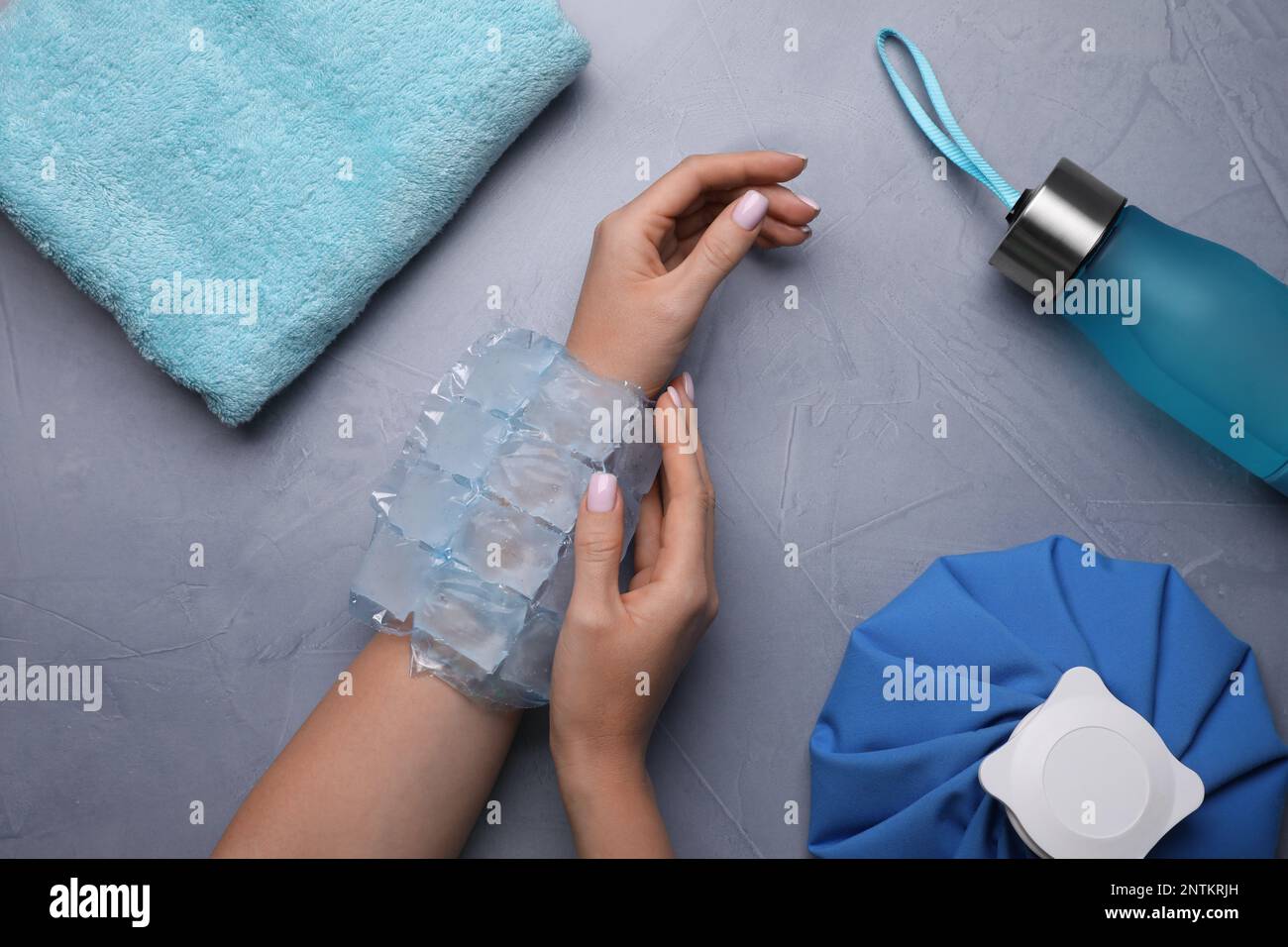 Woman with ice pack at grey table, top view. Heat stroke treatment Stock Photo