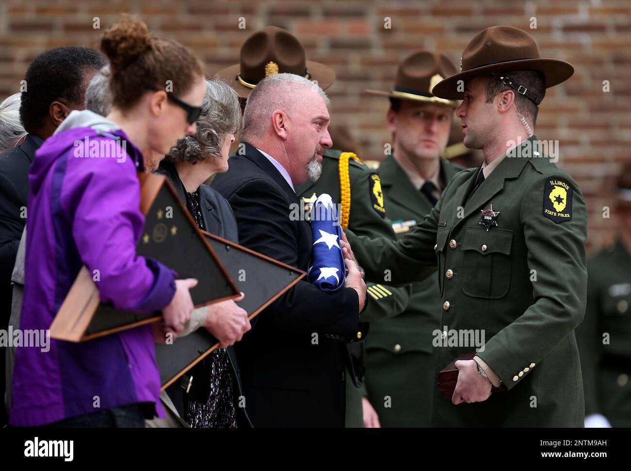 An Illinois State police trooper greets Robert Story Jr., center 
