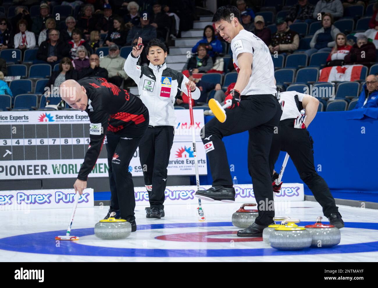 Canada skip Kevin Koe sweeps out a rock from Japan as skip Yuta