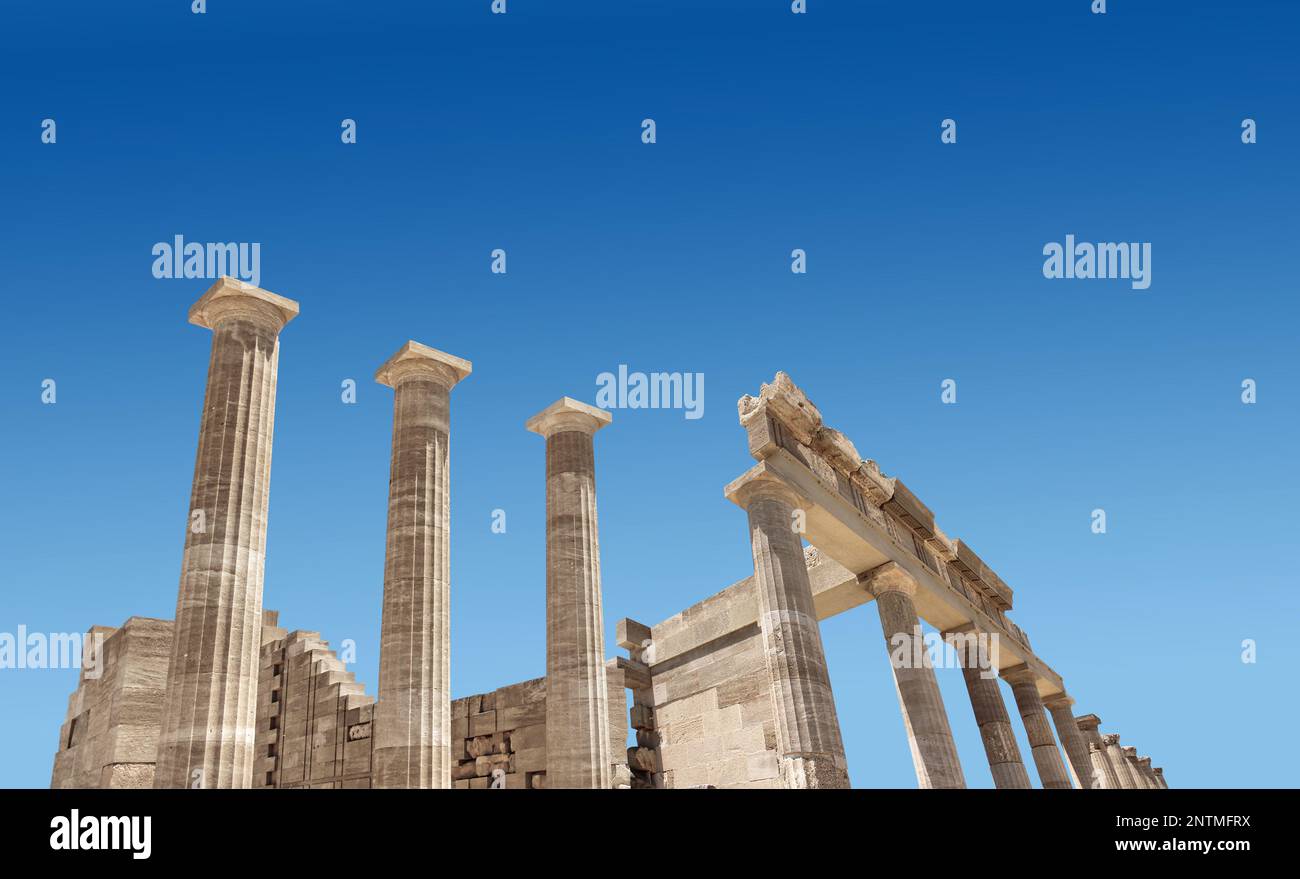 Ancient Greek antique temple facade stone ruins and columns against blue sky Stock Photo