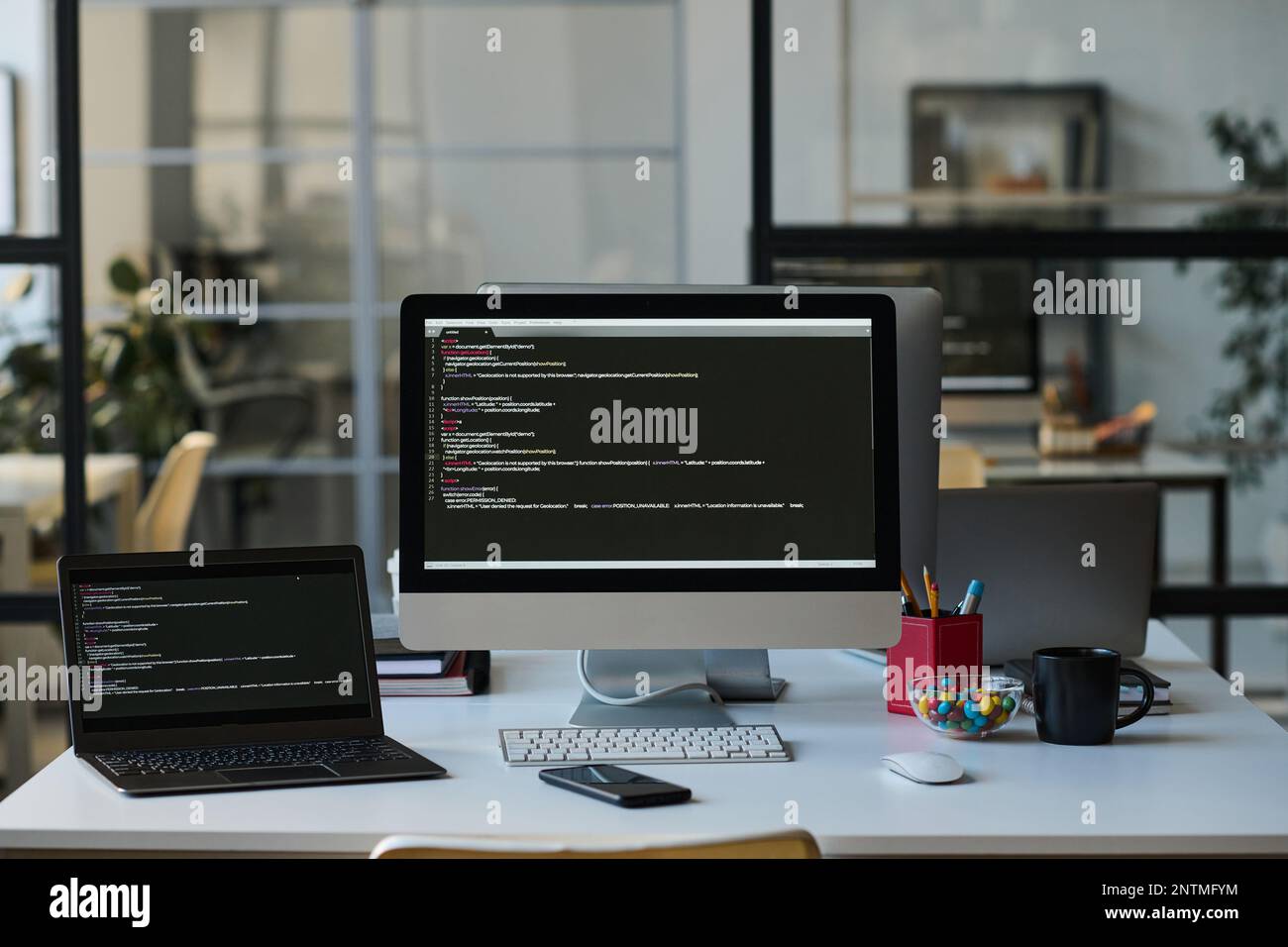 Workplace of developer with computers with programming codes on the screens on table Stock Photo