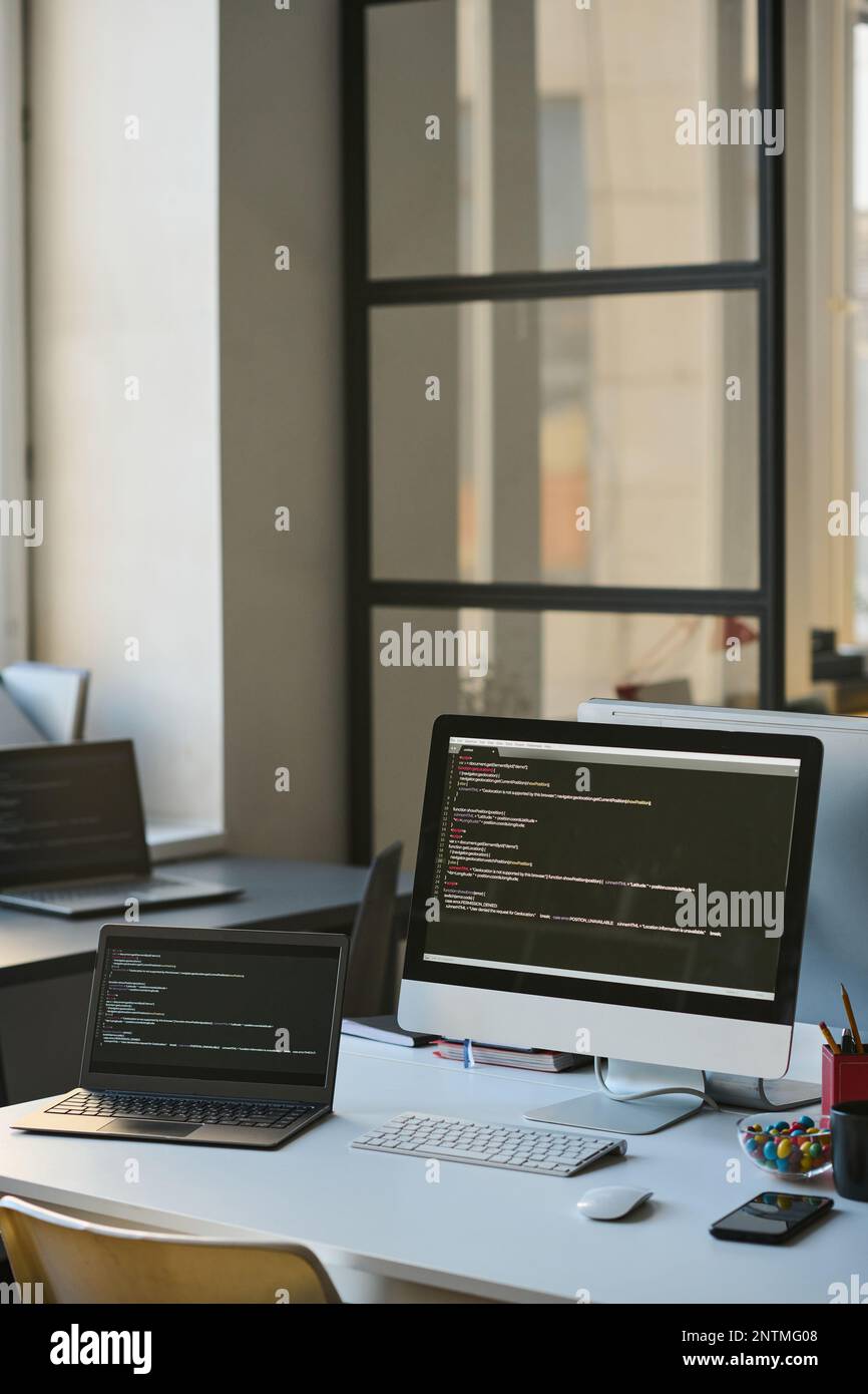 Vertical image of computers with codes on the screens standing on ...