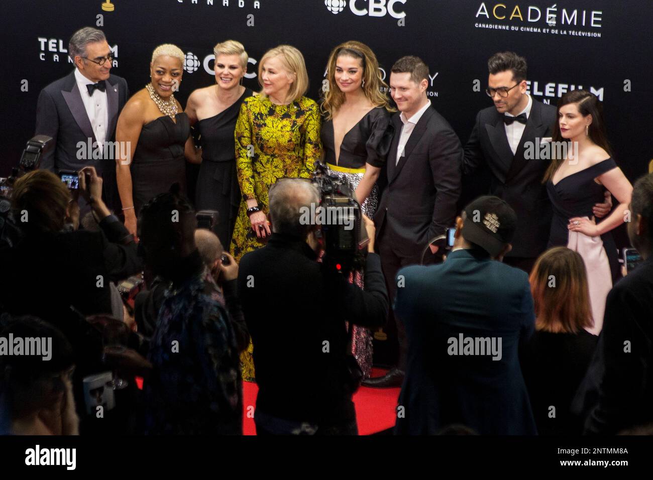 The casting members of “Schitt’s Creek” pose for photos on the red