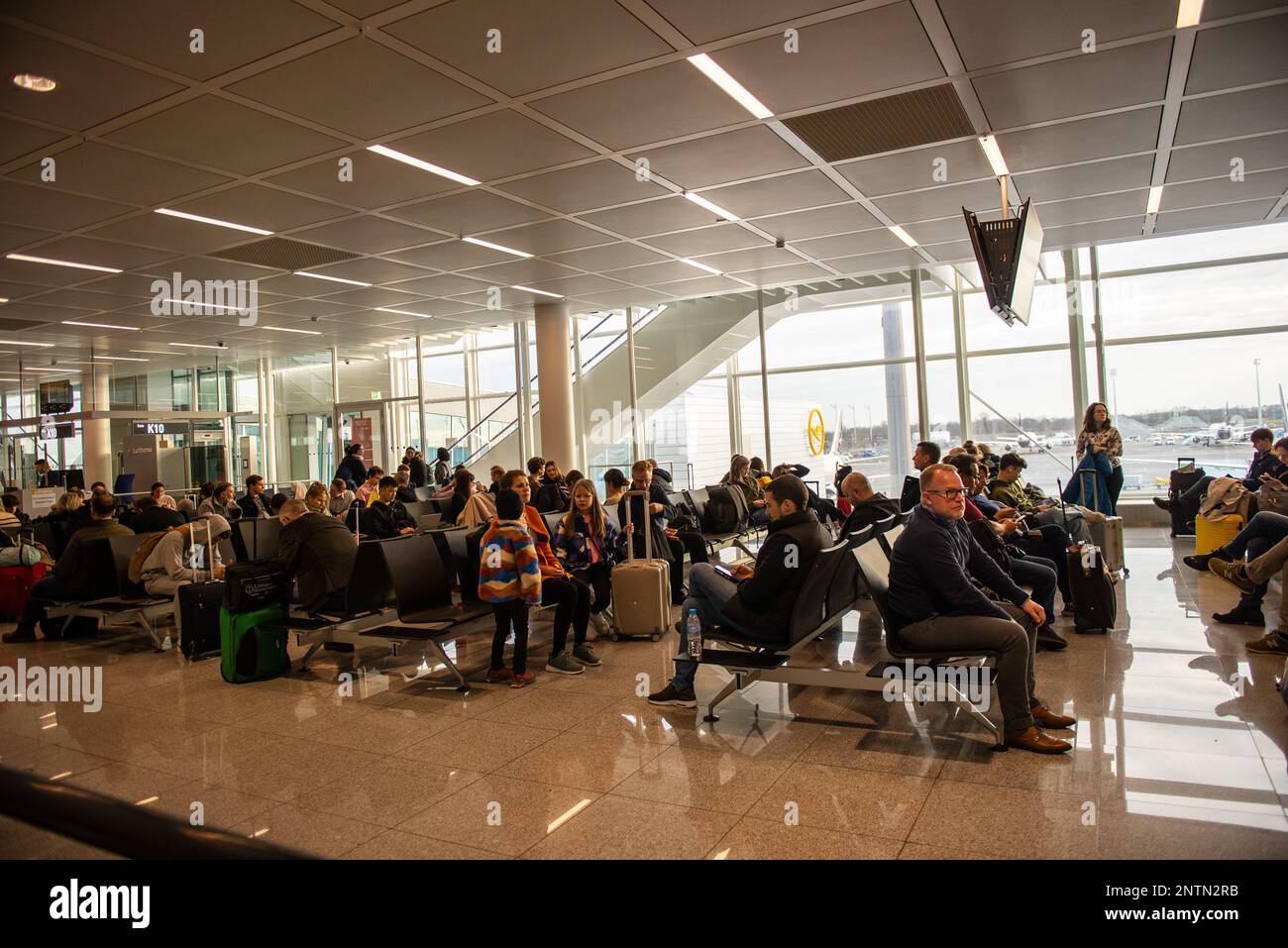 Munich,Germany- February 20,2023:Passengerswait in an airport concourse for their flights to be called Stock Photo