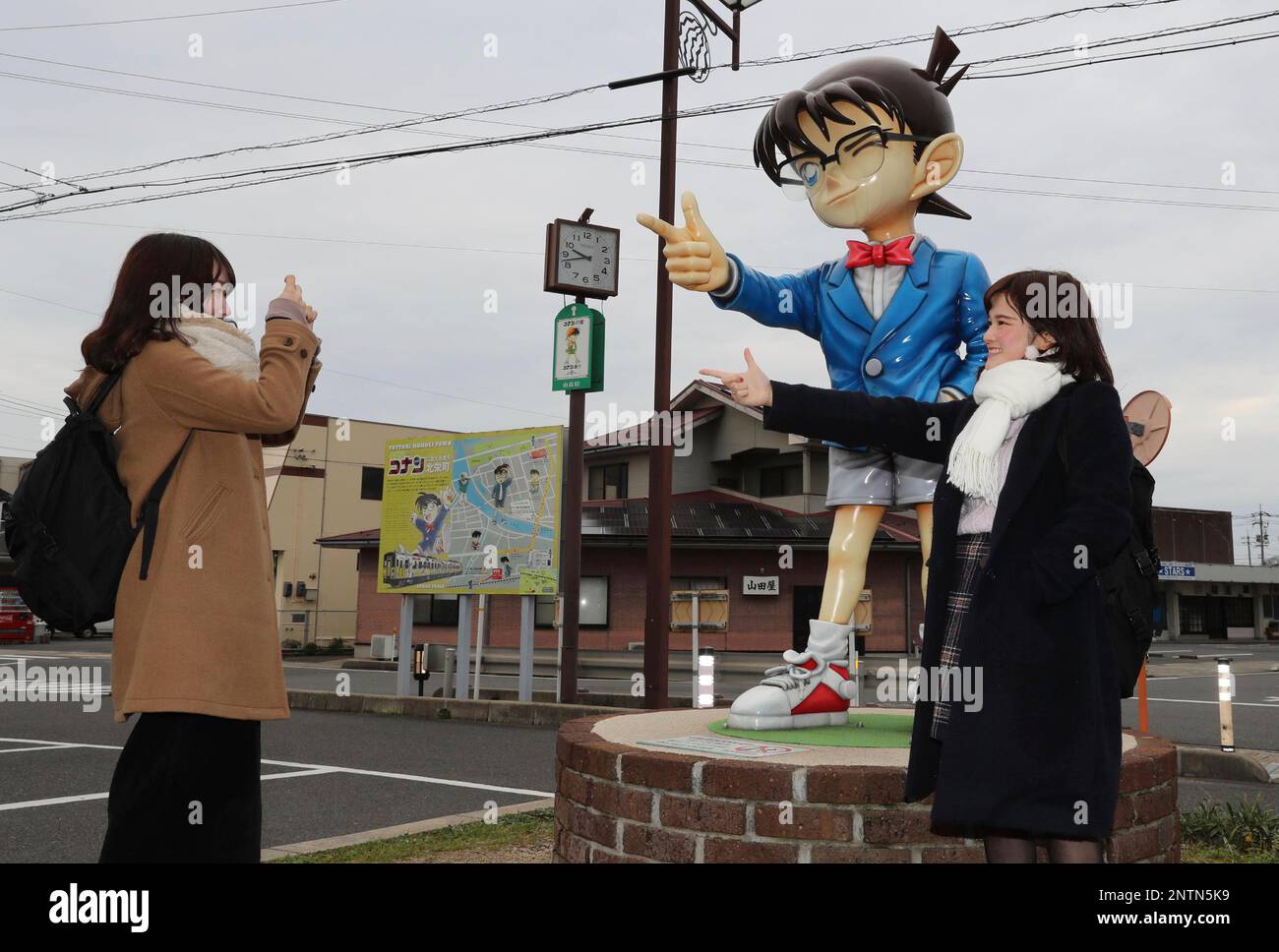 Visitors take pictures with a statue of Detective Conan, a manga character, in front of Yura