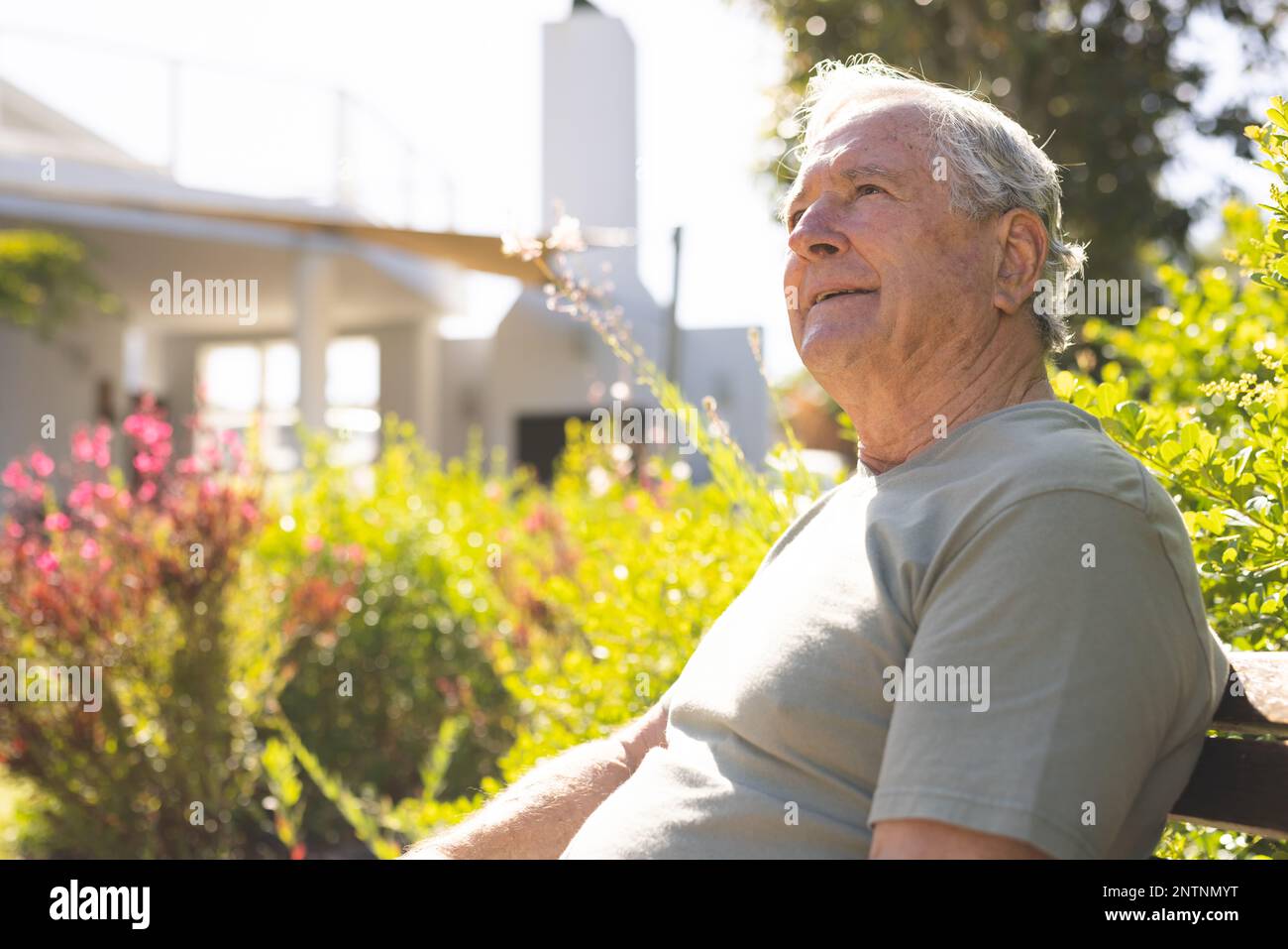 Happy senior caucasian man sitting and walking away in garden Stock Photo