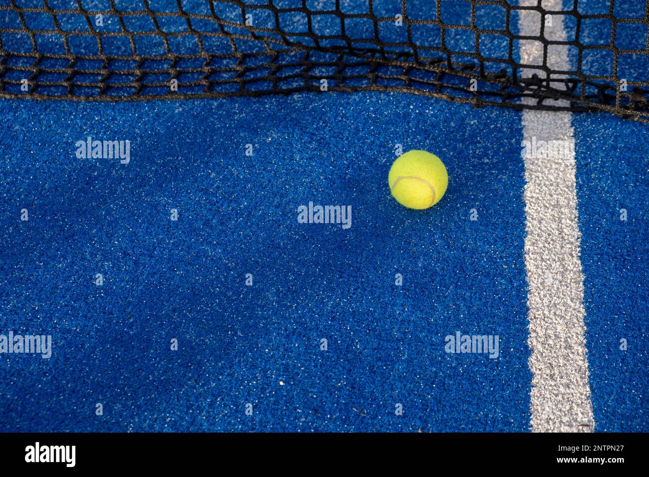 paddle tennis ball in the net of a blue paddle tennis court Stock Photo