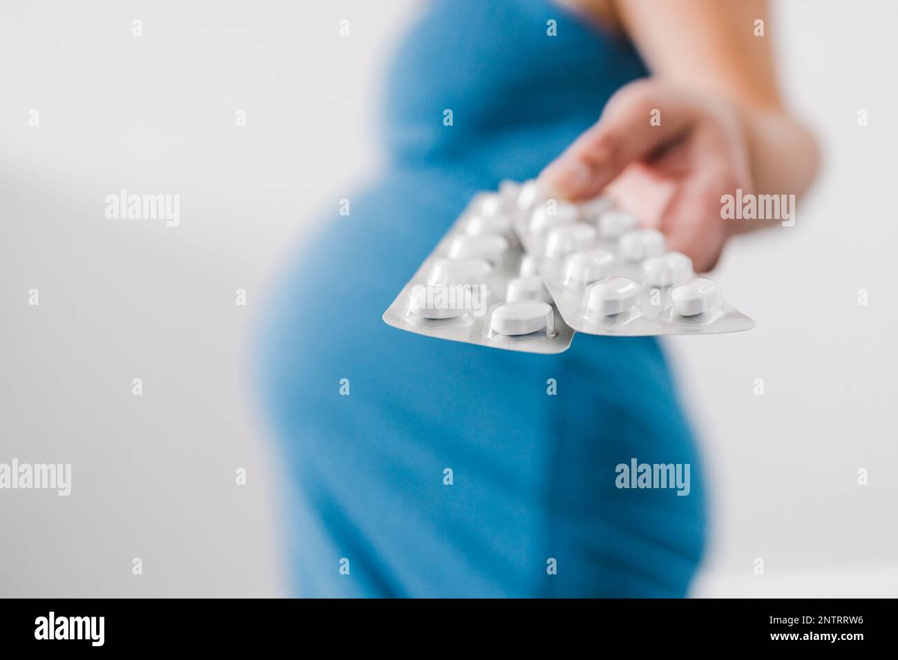 pregnant woman holding multivitamins tablets in her hand and showing