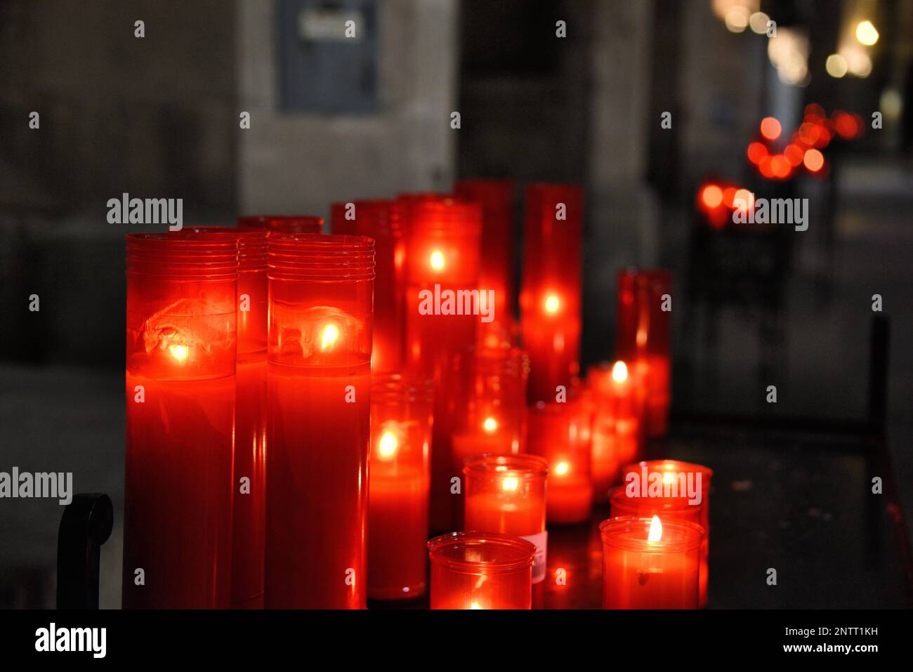 Memorial candles lit in a church for prayers of remeberance. Red casing