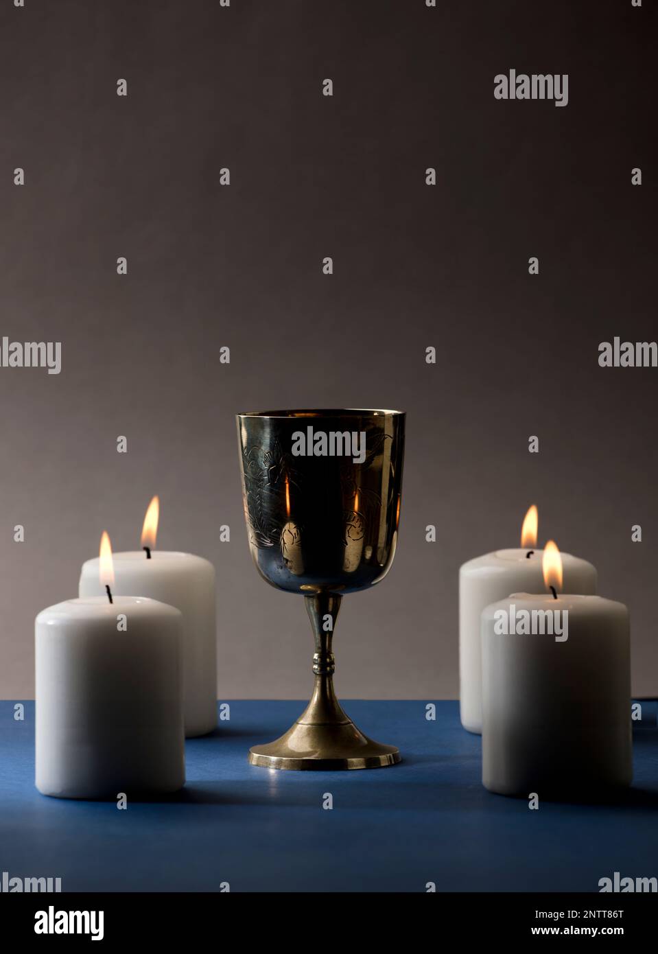 Golden Christian chalice with 4 candles with flames, blue altar, brown