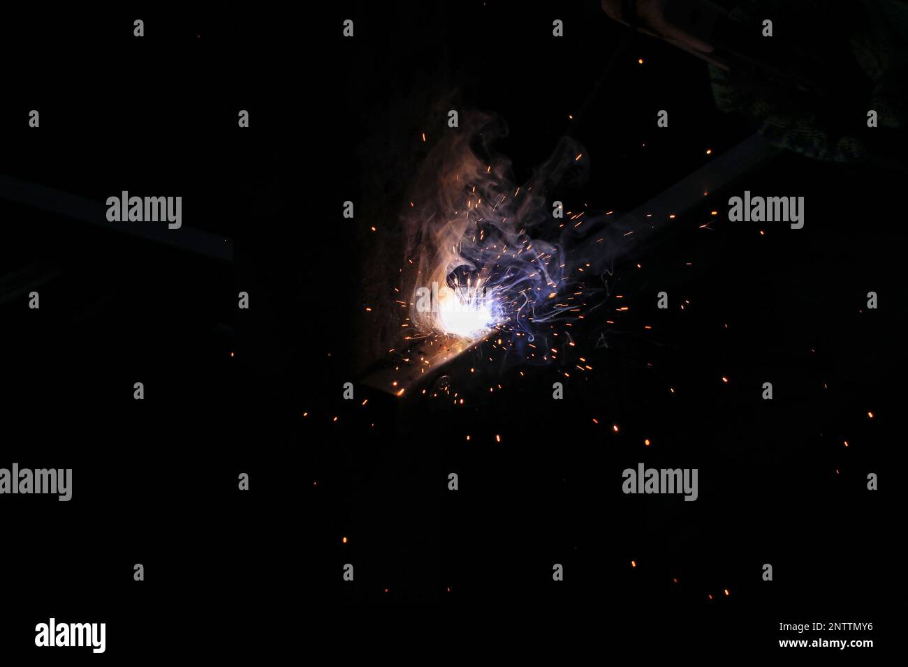Workers welding steel making beautiful colorful sparks in abstract shapes. Stock Photo