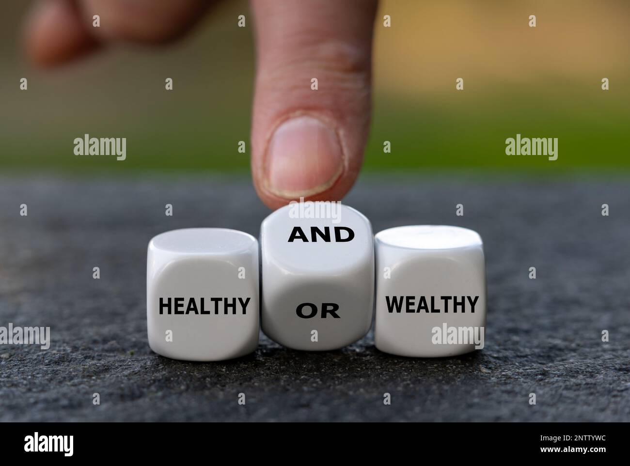 Hand turns dice and changes the expression 'healthy or wealthy' to 'healthy and wealthy'. Stock Photo