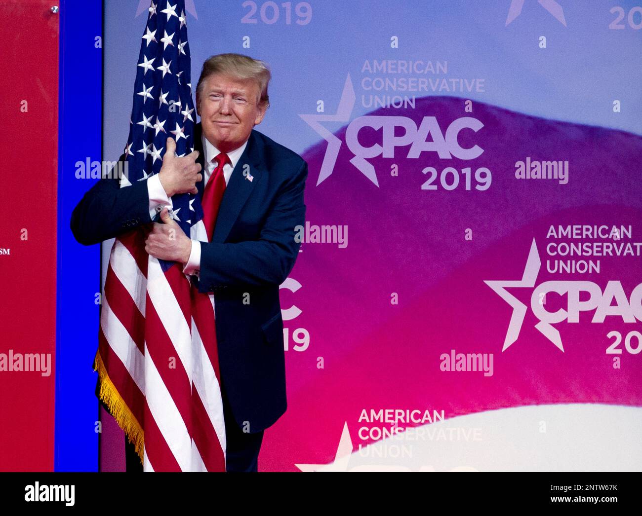 President Donald Trump hugs the American flag as he arrives to speak at ...