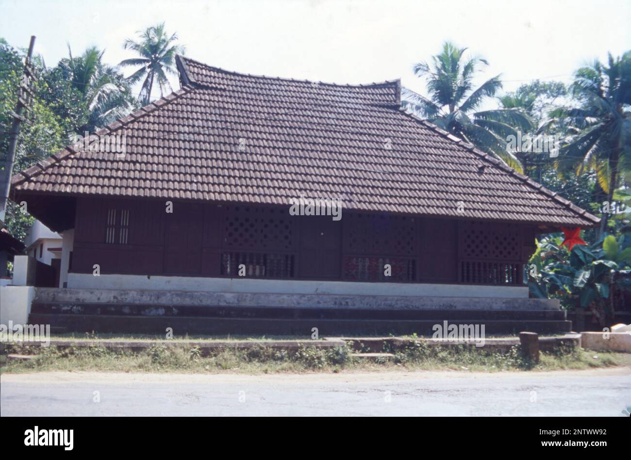 Kerala Houses:- The most distinctive visual form of Kerala architecture is the long, steep sloping roof built to protect the house's walls and to withstand the heavy monsoon, normally laid with tiles or thatched labyrinth of palm leaves, supported on a roof frame made of hard wood and timber. Kerala is a state that receives rainfall for at least 6 months in a year and for such a climate, sloped roofs are always the better. Kerala architecture follows Thatchu Shasthra, a science of carpentry that governs the building/construction nuances. Stock Photo