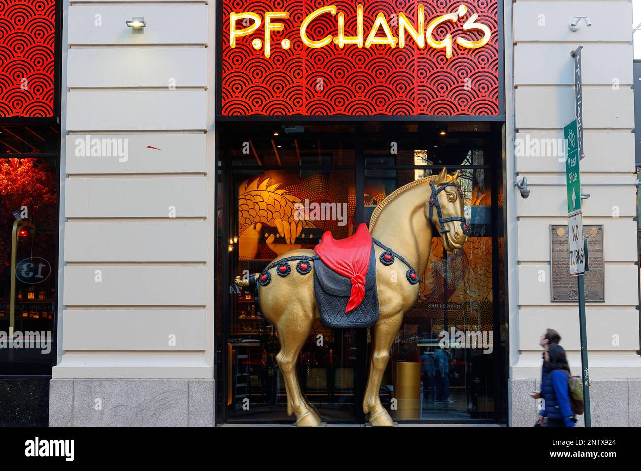 People walk past a large horse statue outside the P.F. Changs, 113 University Pl, New York location in Manhattan's Greenwich Village neighborhood. Stock Photo