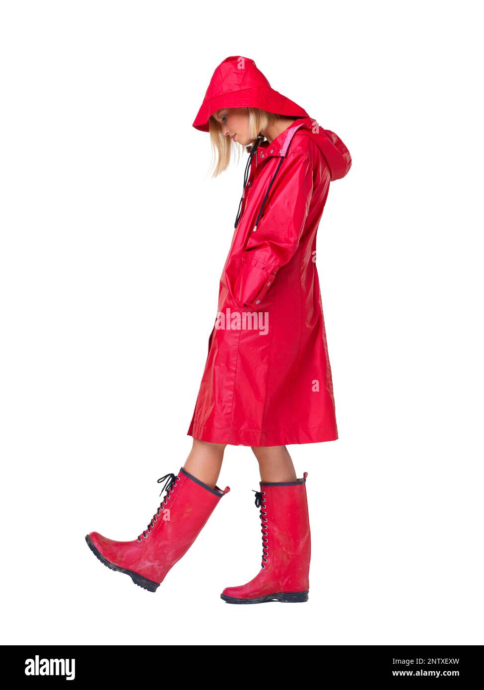 Why does it always rain on me. Woman wearing a red raincoat, hat and boots with her head looking down and hands in her pockets- full length. Stock Photo