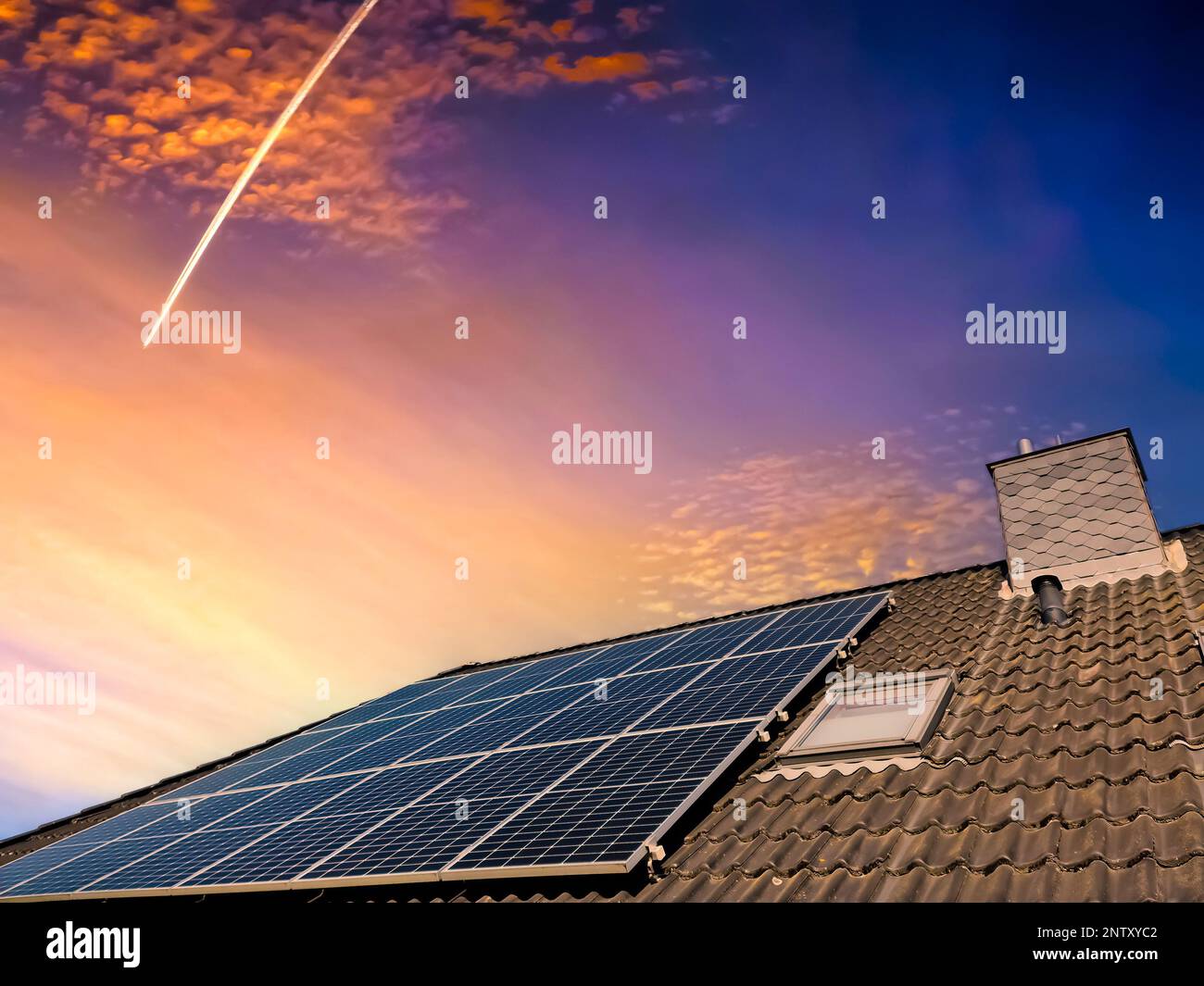 Colorful sunset on solar panels producing clean energy on a roof of a ...
