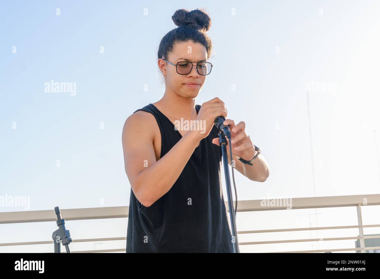 portrait of young latino sound engineer man, with glasses, concentrated, working installing microphone on a tripod. copy space. Stock Photo