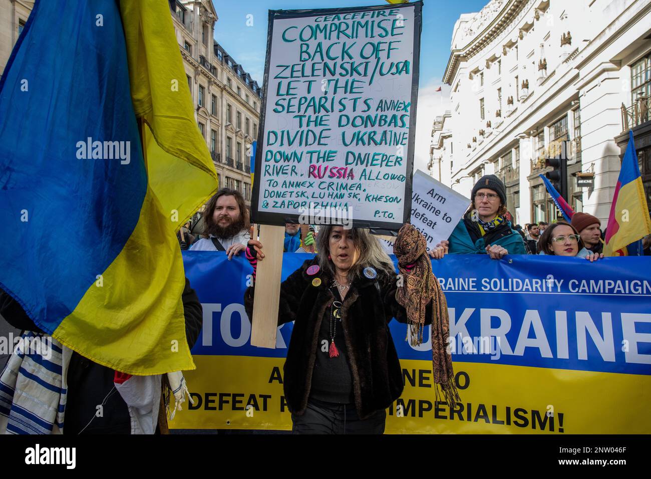 London, UK. 25th February, 2023. A woman holds a sign in front of supporters of Ukraine Solidarity Campaign staging a counter-protest to a march by Stop The War Coalition (StWC) and the Campaign for Nuclear Disarmament (CND) calling for a ceasefire and negotiated settlement in Ukraine. The counter-protest was joined by human rights and LGBT+ activist Peter Tatchell. Credit: Mark Kerrison/Alamy Live News Stock Photo