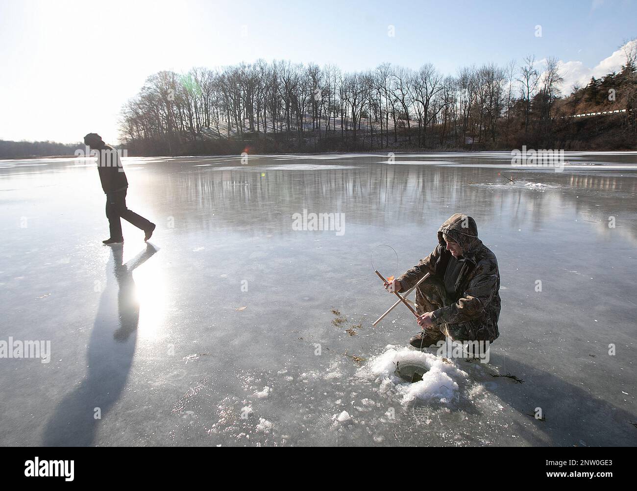 In this Wednesday Jan. 30, 2019 photo, Kenny Dewey, of Wallingford, right, checks on a tipup