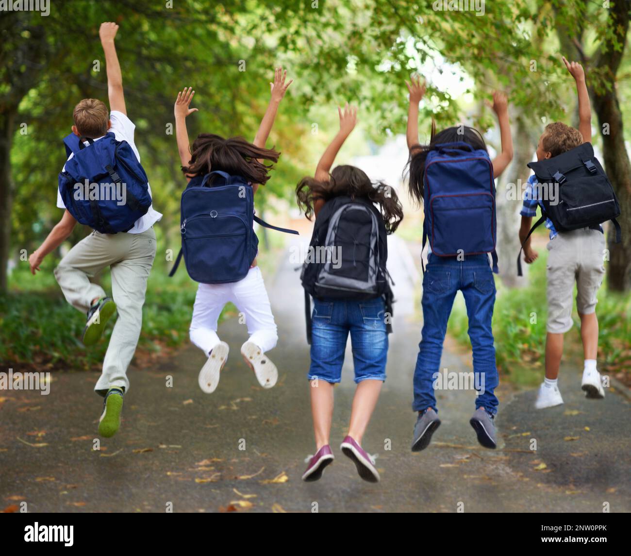 Excited Spring Spring break. Rear view of excited schoolchildren jumping in a row ...