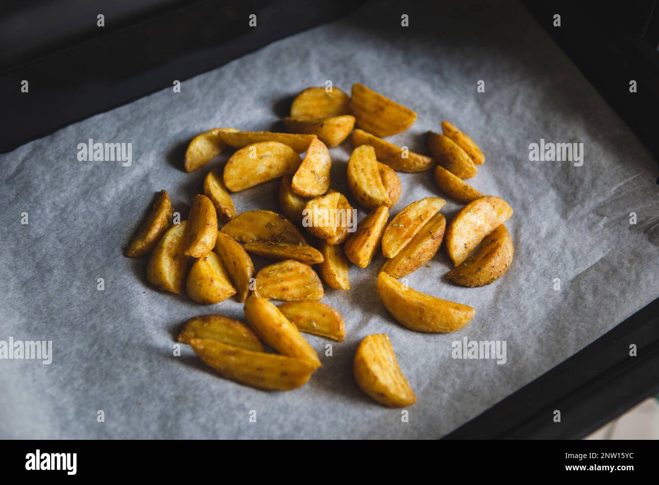 Potatoes on parchment paper prepared for baking in oven at home Stock